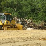 A yellow bulldozer is excavating a pile of debris on a dirt field, with trees in the background. The photo is dated 14/09/2020 at 03:17. Kentucky Builders And Excavating