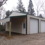 A large metal pole barn garage with three white roll-up doors, a single entry door, and an attached covered side area, surrounded by trees and gravel ground. Kentucky Builders And Excavating