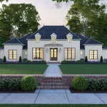 A large, elegant house with light-colored brick, dark roof shingles, multiple windows, and dormers—perfect inspiration if you’re planning to build a house in Kentucky—surrounded by manicured lawns, shrubs, trees, and a brick walkway leading to the front door. Kentucky Builders And Excavating