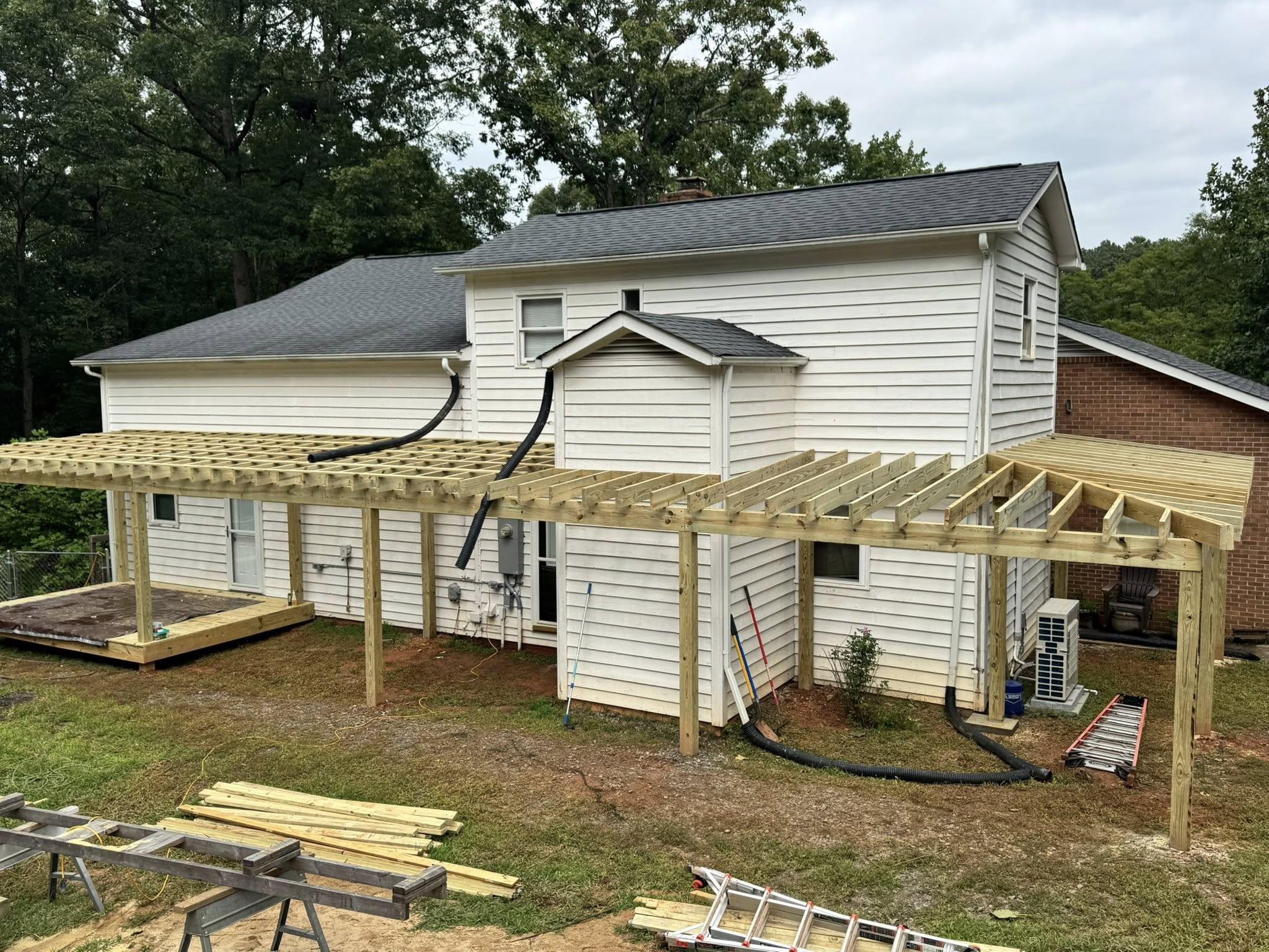 Construction site showing the foundation and structural framing for a new wrap around porch addition with posts and beam system visible