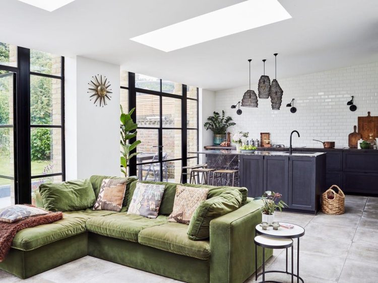 Open floor plan farmhouse great room with kitchen island, wood beam ceiling separation between kitchen and living area, farmhouse dining table, natural light, efficient family layout